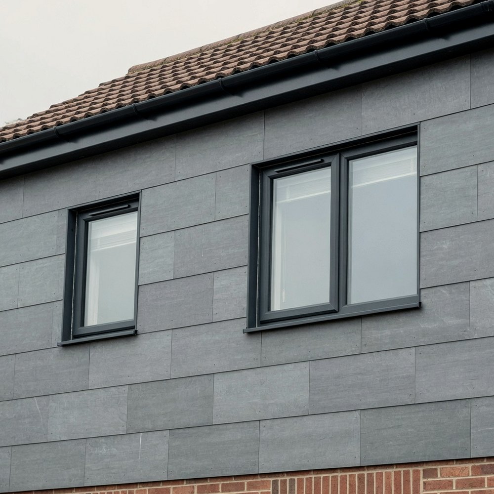 Grey fibre-cement cladding on the upper storey of a house with a tiled roof